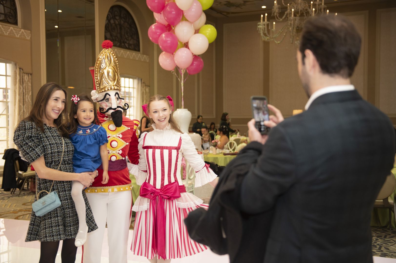 Family posing for a picture beside a nutcracker character and a ballerina